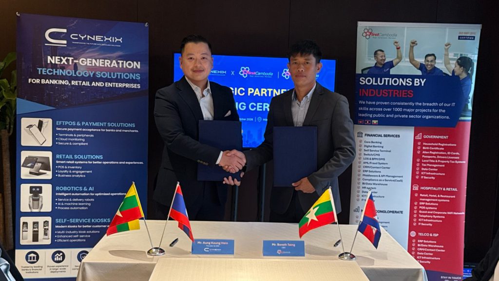 Aung Kaung Hein and Borath Taing shaking hands after the signing, each holding the signed agreement.