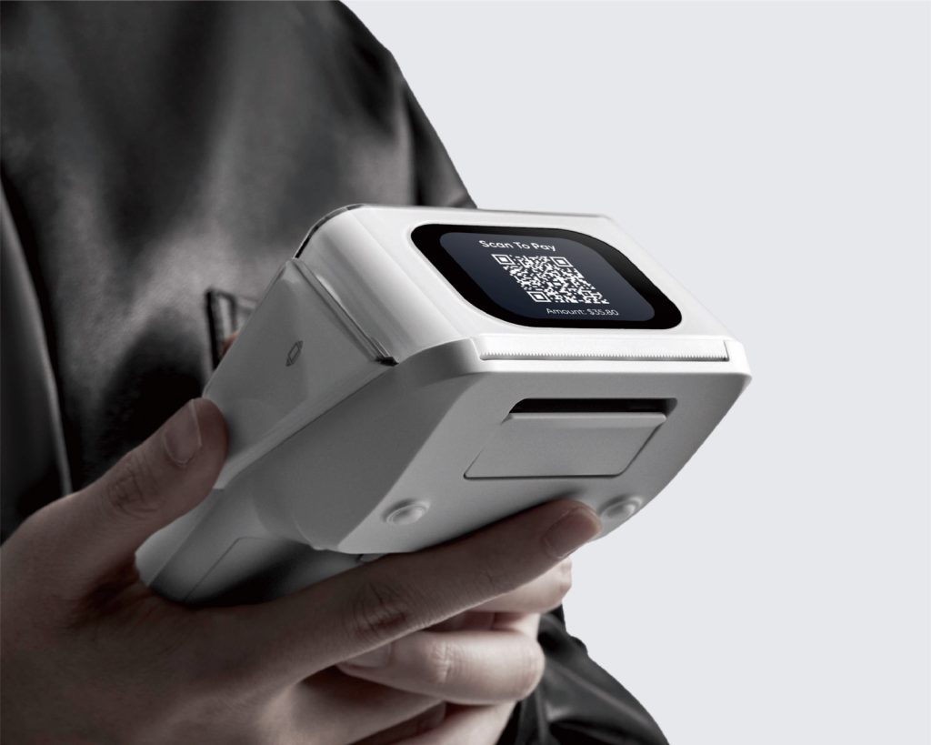 Hand holding a portable payment terminal with a QR code on its screen